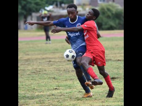 Ian Allen/PHOTOGRAPHER
Michael Graham (left) from Jamaica College and Recardo Burns  of Bridgeport High School compete for the ball during their Manning Cup football match at the Stadium East playing field yesterday. JC won 5-0.