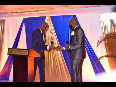 Nehemiah Perry (left), immediate past president of the Jamaica Association of Insurance and Financial Advisors, hands over the baton of responsibility to his successor, Otis Hamilton, at an inauguration ceremony at Terra Nova Hotel on Saturday. Hamilton is