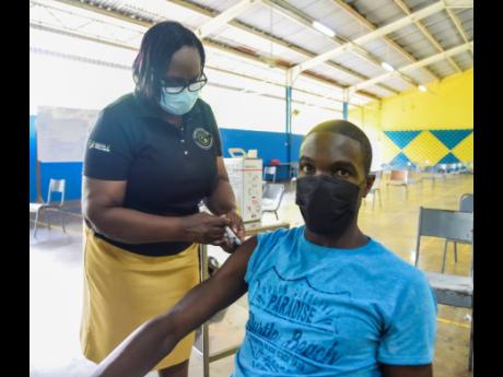 Public health nurse Hopelyn Mullings administers the Pfizer COVID-19 vaccine to Damion Lewis at Tarrant High School on Saturday. 