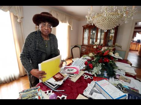 Mother Mary Patterson stands at her dining room table in her Memphis, Tennessee home. The material on the table was used by Patterson in her recent campaign to post historical markers about Church of God in Christ leaders. In the Church of God in Christ, w