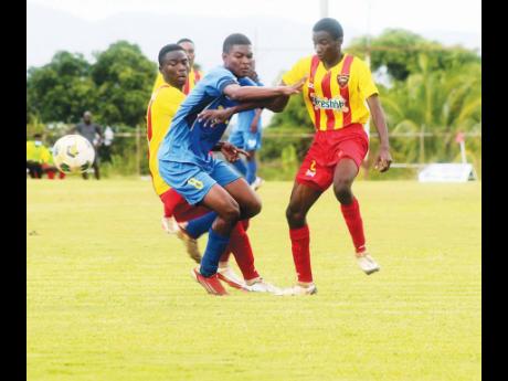 
Clarendon College’s, Christopher Hew (centre) is swarmed by Cornwall College defenders Giovanne Bruce (left) and Deshaun Talbert during the ISSA/daCosta Cup football match at St Elizabeth Technical High School Sports Complex yesterday. Clarendon won 2-1