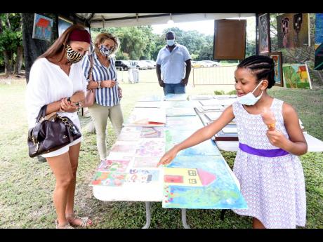 Young visual artist, seven-year-old Jacey Bulgin, shows off some her beautiful artwork, under the watchful eye of her dad Hilroy in the distance, during a craft fair at the Jamaica Horticultural Showground in St Andrew on Saturday.