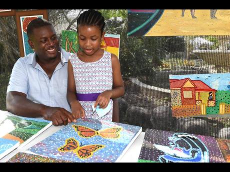 Artist Hilroy Bulgin marvels at his seven-year-old daughter Jacey, who joined him in selling artworks they both produced. They were attending a craft fair at the Jamaica Horticultural Showground in St Andrew on Saturday. 