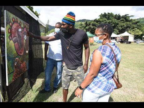 Art lovers are enraptured by one of Hilroy Bulgin’s artworks during a craft fair at the Jamaica Horticultural Showground in St Andrew on Saturday.