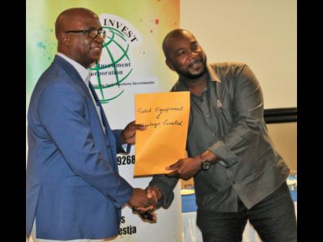 Al Taylor (right) of Solid Equipment and Haulage is a happy man as he accepts the lease contract for him to cultivate 50 acres at the Mango Agro-Park in Spring Plains, Clarendon, during Tuesday’s investment breakfast at The Jamaica Pegasus hotel in New K