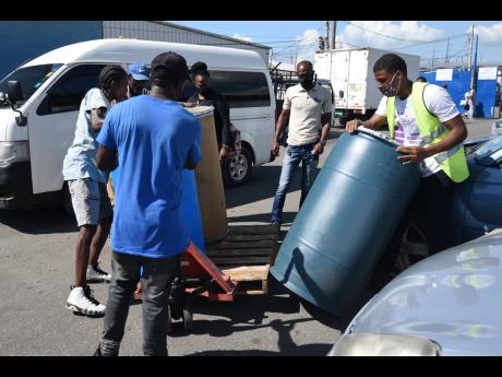 Several persons were seen collecting or waiting to collect barrels at Universal Freights on Industrial Terrace in Kingston. Some complained that the process is too time-consuming. 