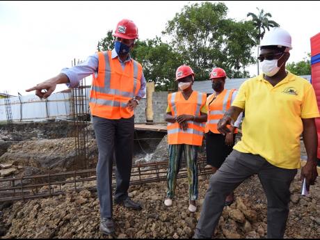 Robin Levy (left), chief executive officer, Jamaica Co-operative Credit Union League, ask questions of Andre Josephs (right), contractor for the  new branch office in Morant Bay, St Thomas, during a visit of the site after the official groundbreaking cerem
