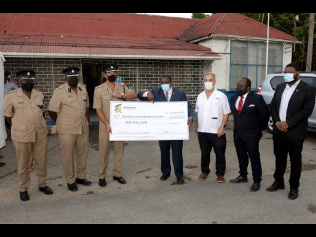 Minister of Transport and Mining Robert Montague (centre) presents a symbolic cheque for $10 million from the Toll Authority of Jamaica for the renovation of the Ferry Police Station in St Andrew to Deputy Police Commissioner Clifford Blake. The presentati