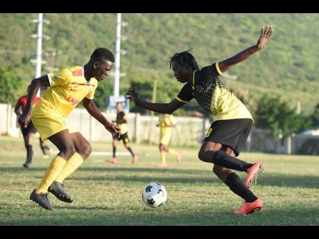 
Charlie Smith’s Imarie Foster (left) keeps his focus against the wily moves of Kingston Technical High School’s Maqan Aldridge during their Manning Cup quarter-final game at the Stadium East field yesterday. 