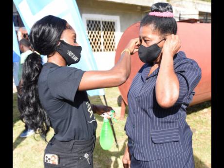 Elaine Thompson-Herah (left) helps fit a face mask on her grandmother, Hycenth ‘Gloria’ Thompson, during a community treat in Banana Ground on Saturday. Hycenth Thompson’s animated celebration after Thompson-Herah’s 100m Olympic victory in Tokyo we