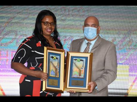 Camille Foster collects two awards – one for her and the other for her late husband ­– from Christopher Zacca, president and CEO of Sagicor Group Jamaica during the Sagicor Community Heroes Awards held at The Jamaica Pegasus on Tuesday.
