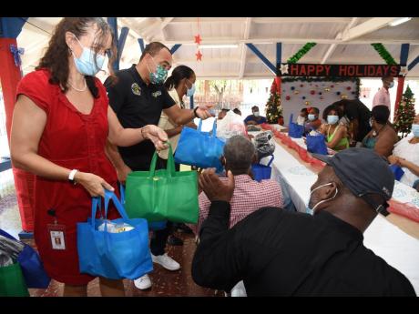 Health and Wellness Minister Dr Christopher Tufton (second left) and Bellevue Hospital Chairman Dr Diana Thorburn (left) hand out care packages at the Corporate Area-based medical facility’s annual patients’ banquet yesterday.