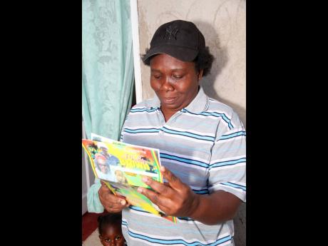 Claudette Brown of Lime Hall, Clarendon, fights to hold back the tears as she looks through the funeral programme of her late father, Phillip Brown.