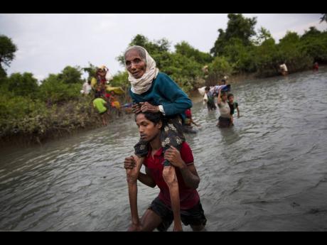 A Rohingya Muslim carries an elderly woman through water after crossing the border from Myanmar into Bangladesh, near Palong Khali, Bangladesh, in November 2017. Frances Haugen, a former senior Facebook staff member, testified that Facebook was used by the