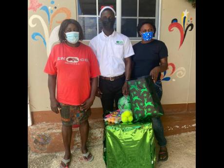 Nowell Lewin (centre) shows off some of the gifts donated to the St Monica’s Boys’ Home in Chapelton, Clarendon, on Christmas Day.