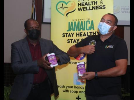 Health and Wellness Minister Dr Christopher Tufton (left) presents Jamaica Hotel and Tourist Association President Clifton Reader with a batch of 5,000 COVID-19 home-testing kits for tourism workers during a ceremony at the Montego Bay Convention Centre in
