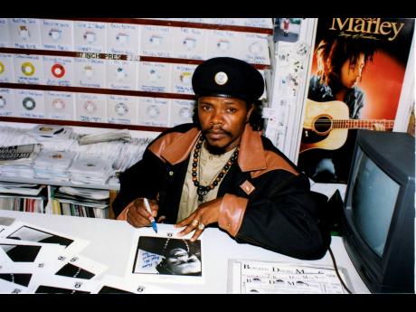 
A young Luciano signs autographs with a poster of Bob Marley in the background. Marley is one of many icons the 57-year-old holds in high regard.