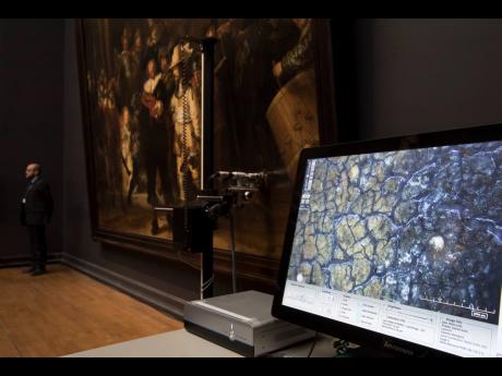 In this 2018 photo a microscopic image enlarging a 4x6 millimetre part of the painting on Rembrandt’s Night Watch, which will be restored in the public eye, is seen on a screen next to the painting at the Rijksmuseum in Amsterdam, Netherlands. Rembrandt 