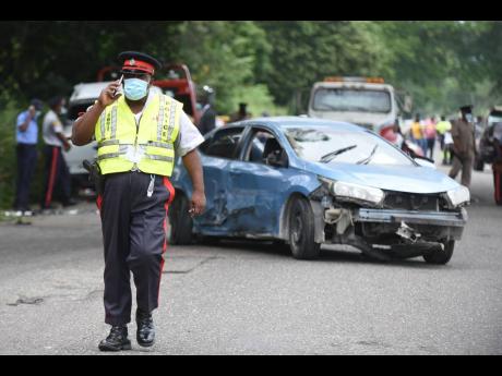 A police officer walks away from the scene of the fatal accident in which Kevin Smith lost his life in Linstead, St Catherine, on October 25, 2021.
