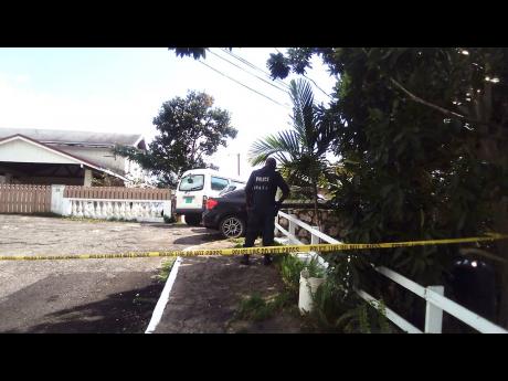 A policeman is seen near the Kirkland Close, St Andrew, home of businessman Donald Anthony Thompson, whose body was found hanging on Sunday. Wife Paulette Thompson said he feared going to jail for mounting back taxes he could not reconcile.