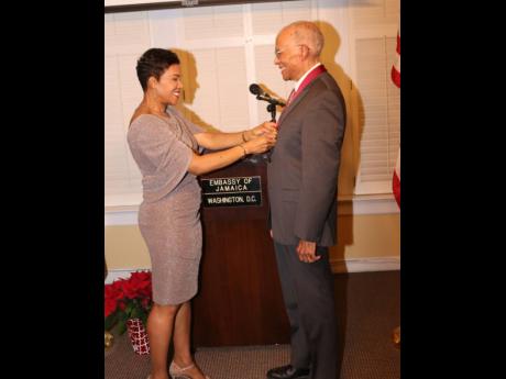 Jamaican Ambassador to the United States of America Audrey Marks pins Economist Professor Donald J. Harris, who was conferred with Jamaica’s third-highest national honour, the Order of Merit for his contribution to national development at a ceremony at t