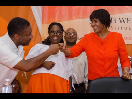 File 
Phillip Paulwell greets Portia Simpson Miller with a fist bump as her successor in St Andrew South Western, Angela Brown Burke, looks on during the constituency conference in August 2017.