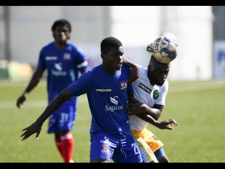 Dunbeholden’s Romario McPherson (front left) and Vere United’s Ricardo Dennis in a battle for possession during yesterday’s Jamaica Premier League match at the UWI-JFF Captain Horace Burrell Centre of Excellence. 