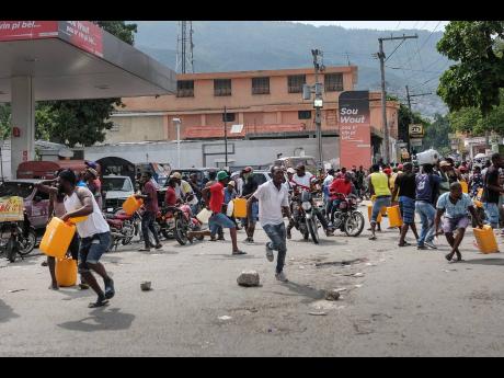 People run for cover as police shoot into the air to disperse a crowd threatening to burn down a gas station because they believed the station was withholding the gas, in Port-au-Prince, Haiti, last October.