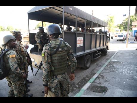 Jamaica Defence Force soldiers gather during a military operation at the intersection of Barry and Gold streets in central Kingston on Monday. Violence has flared in that section of the capital, with a zone of special operations imposed in Parade Gardens n