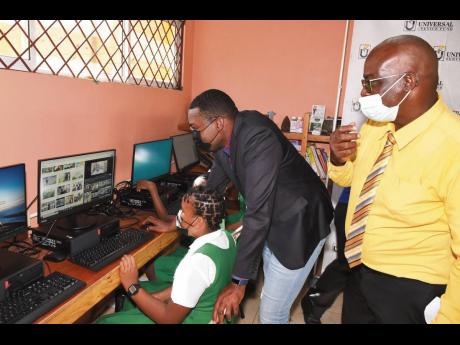 Minister without Portfolio and Clarendon North Central Member of Parliament Robert Morgan (centre) assists grade six student Anecia Simpson in using a computer at the new community access point site at Brixton Hill Primary. Looking on is principal Leon Cla