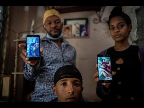 Odlanier Santiago Rodríguez (centre), who was accused of participating in the recent anti-government protests and who was released after 22 days in prison, poses with his uncle Emilio Roman and his daughter-in-law María Carla Milán Ramos, as they show p