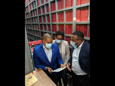 Minister without portfolio in the Office of the Prime Minister Floyd Green takes a look at an original copy of his birth certificate during a tour of the Registrar General’s Department on Friday. The minister was accompanied by RGD CEO, Charlton McFarlan