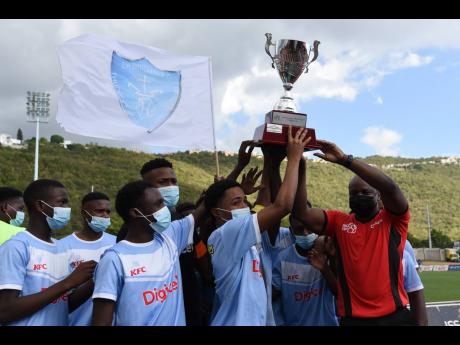 
St Catherine High School players celebrate retaining the ISSA Walker Cup title they earned by defeating Kingston Technichal High School 1-0 at the Stadium East field yesterday.