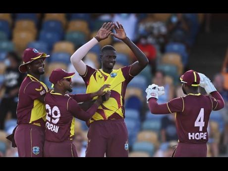 West Indies allrounder Jason Holder (centre) is congratulated by teammates (from left) Romario Shepherd, Nicholas Pooran, and Shai Hope for taking one of the four scalps he had during the first T20 International between his team and England in Barbados yes