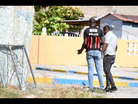Policemen are seen in the community of Dunkirk, east Kingston, on Saturday, after gunmen shot four persons, killing two, the evening before. The attackers targeted a wake. 