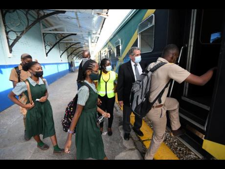 
Jamaica Urban Transit Company Managing Director Paul Abrahams (second right) and Robin Geddes, customer service assistant, observe students boarding a train in Spanish Town on Monday. The passenger train service for students resumed on January 10, one wee