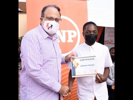 People’s National Party (PNP) President Mark Golding, presents a certificate to Jhaeem Brown, a recipient of the OT Fairclough Trust Fund Scholarship Awards.  