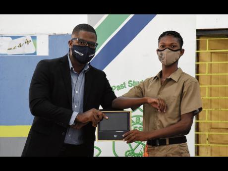 Contributed 
Last year the Vauxhall High School Alumni Association donated 61 tablets to the Windward Road institution. Here, president of the Jamaica Chapter, Timar Jackson, presents grade-nine student Ishmael Small with a tablet.