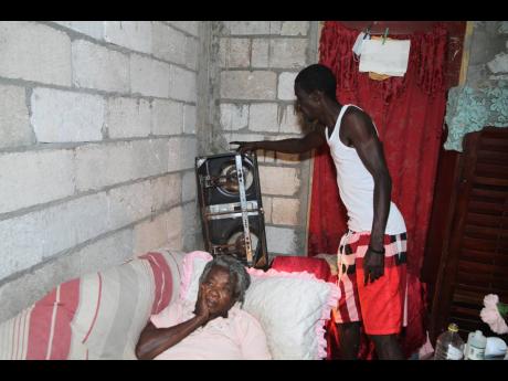 Wayne Reid of Arthur Seat in Crofts Hill, Clarendon, shows a two-burner stove, which no longer works, while his mother, Elmena O’Conner, looks on. Reid quit his job as a taxi operator to take care of his ailing mother, but they are facing financial chall