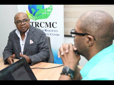 Minister of Tourism Edmund Bartlett speaks to the media while Professor Lloyd Waller, professor of digital transformation policy and governance at The University of the West Indies, looks on during a luncheon on Tuesday. 