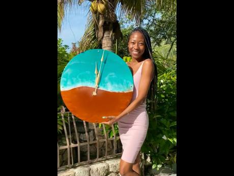 The owner and artistic creator of Aura Sphere Jamaica, Sara Palmer, beaming with great pride as she holds one of her ‘timeless’ designs – a unique clock.