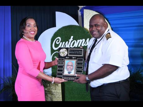 Jamaica Customs Agency CEO Velma Ricketts Walker (left) presents the Employee of the Year Award to Damean Beckford, manager of the Data Entry Unit in Kingston, at the agency’s employees awards and recognition ceremony at its King Street offices in downto