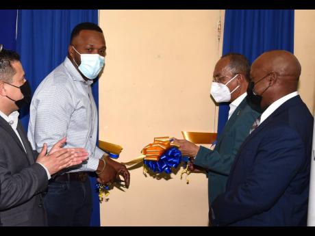 
Minister of National Security Dr Horace Chang (second right), and entertainer Jeffrey ‘Agent Sasco’ Campbell (second left), cut the ribbon to open the Black Diamond Music Studio at the Metcalfe Street Secure Juvenile Remand Centre in Kingston on Wedne