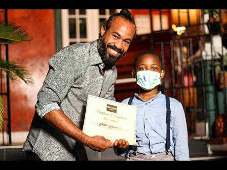 LEFT: While eight-year-old Joshua Johnson’s smile is hidden by his mask, there is no doubt that he shares the same joy that Jonathan Buchanan has as he collects his certificate of completion.