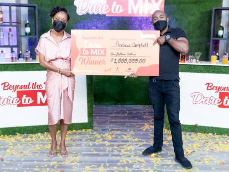 Smirnoff Jamaica’s Brand Manager, Lyshon Davis (left), presents Andrew Campbell with a cheque for $1 million. 