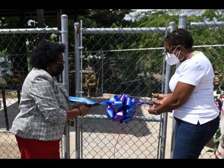 Mona Sue-Ho (left), senior manager of social development at the Jamaica Social Investment Fund, and Dr Angela Brown Burke, member of parliament for St Andrew South Western, cut a ribbon to mark the official opening of green space constructed at the Greenwi