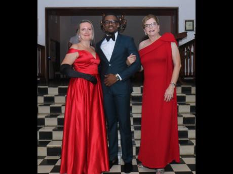 Strikingly red! Hanover Charities’ Katrin Casserly (left) and her co-chair Jennifer Flanagan were ‘reddy’ for that pose with Calvin Lewis (centre), IT manager, Round Hill Hotel and Villas, at the Hanover Charities annual Sugarcane Ball at Round Hill 