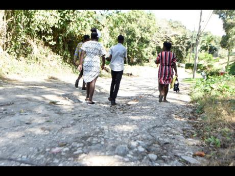 Residents walk along an unpaved road in Golden Spring on Sunday.
