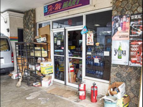 A shattered glass door at the entrace to the Fi-Wi Mart service station in Red Hills, St Andrew, bears evidence a shootout at the location after police were challenged by robbers at the facility on May 17, 2021. Henrique Hemmings, the 16-year-old ward of t