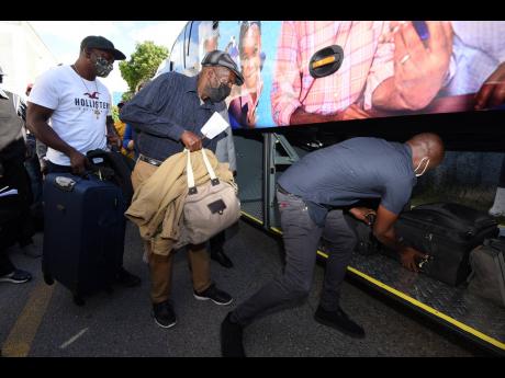 Farm workers have their luggage packed in a storage compartment as they prepare to be bussed from the Ministry of Labour and Social Security office at East Street, Kingston, to the Norman Manley International Airport on Thursday. Ninety-five season workers